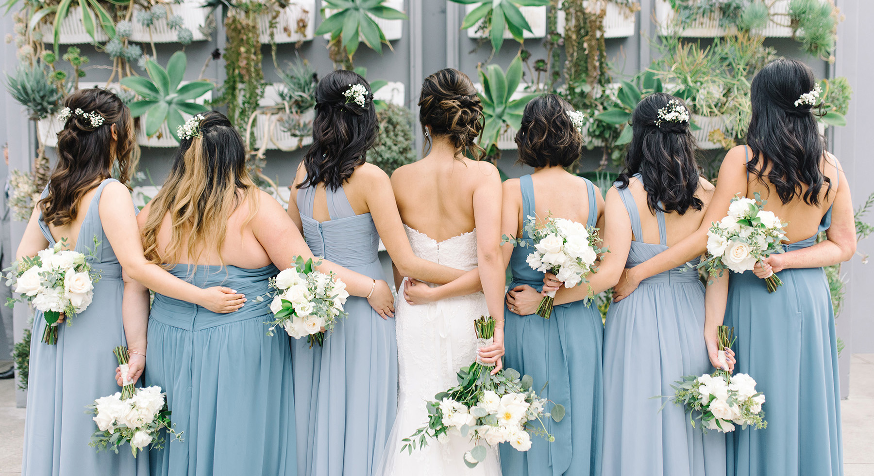 Bride and bridesmaids standing next to each other and facing away from the camera