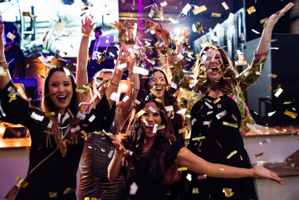 four event planners throwing gold confetti up in the air