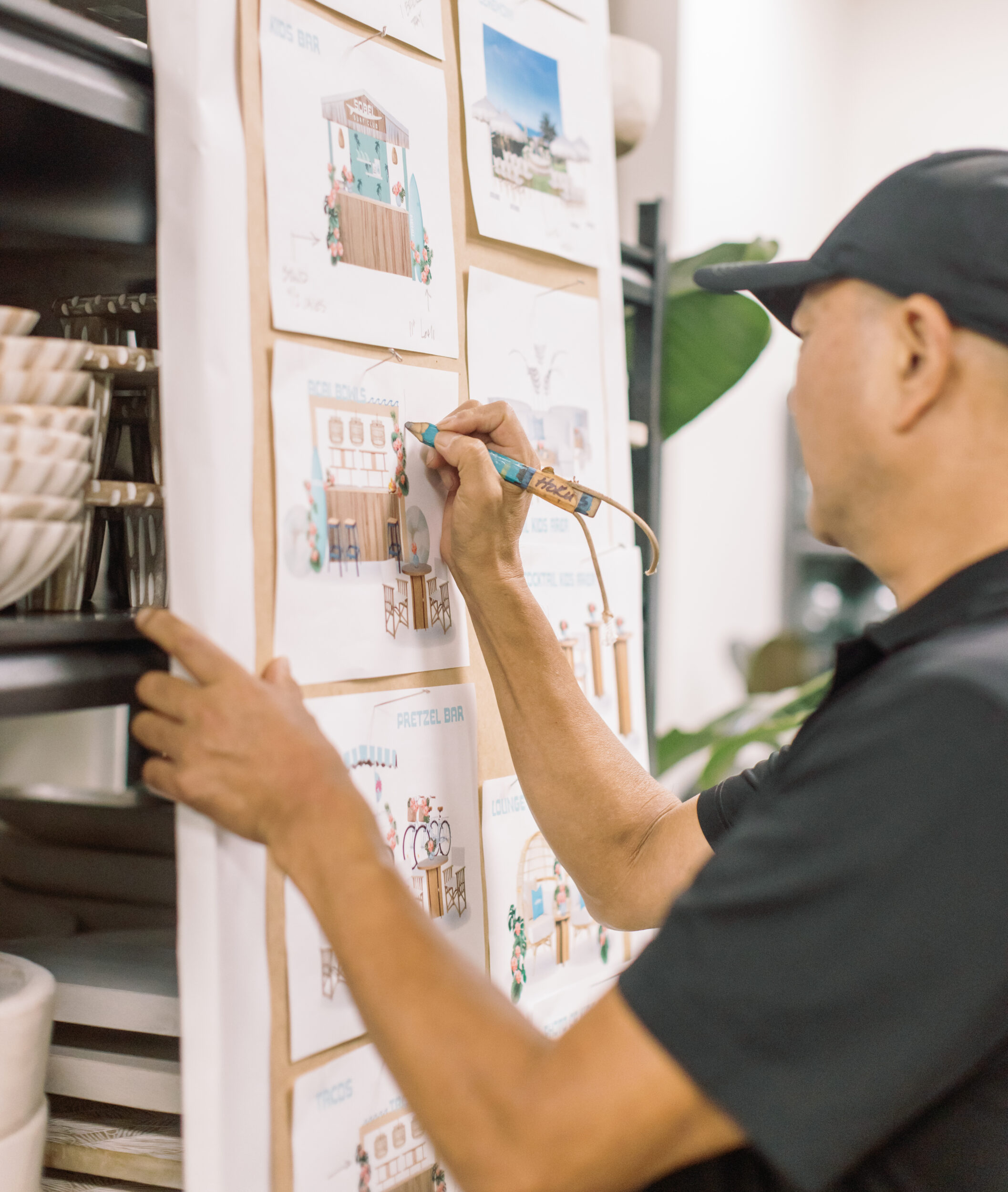 Team member sketching designs on a board pinned with photos.