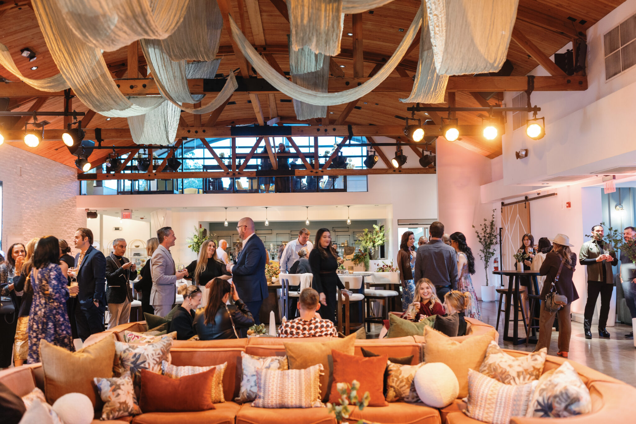 Guests mingling around lounge seating beneath draped fabric in an event space.